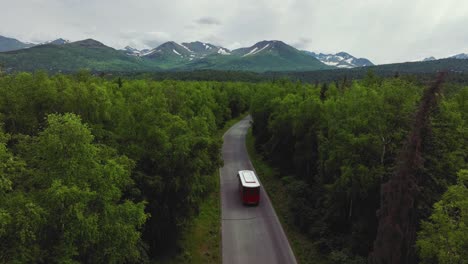 Anchorage-Trolley-Tour-Bus-Traveling-Across-The-Road-With-Forest-Trees-In-Anchorage,-Alaska
