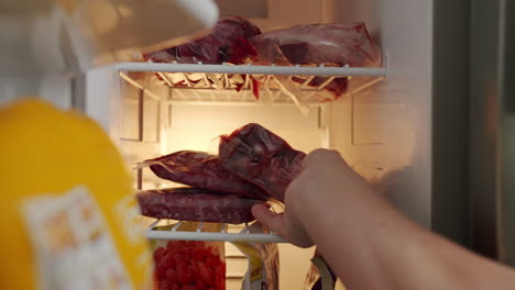 Nahaufnahme-Einer-Hand,-Die-Die-Kühlschranktür-öffnet-Und-Versiegeltes-Rotes-Fleischsteak-Auf-Das-Gefrierregal-Legt,-4K