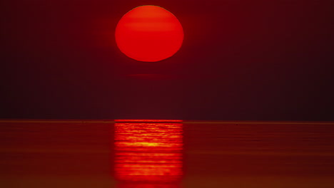 Static-shot-of-sun-rising-over-the-Pacific-ocean-over-the-red-sky-with-the-view-of-sea-waves-below-at-dawn
