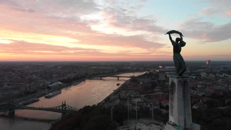 Cinematic-aerial-reverse,-Liberty-Statue-in-Budapest,-colorful-sunrise