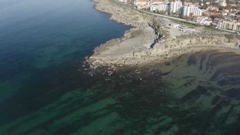 Aerial-drone-view-of-Zoom-in-of-Lighthouse-in-Sao-Pedro-do-Estoril-spot-in-Sao-Pedro-do-Estoril,-Greater-Lisbon,-Cascais-in-background