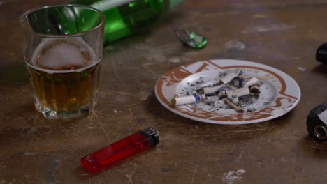 Beer-bottle-glass-gun-and-ashtray-on-wooden-table
