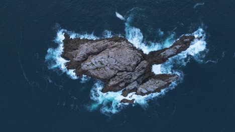 Einzigartige-Luftaufnahme-Von-Wellen,-Die-Auf-Eine-Fischfelsenhöhle-Krachen,-Umgeben-Von-Tiefblauem-Meerwasser