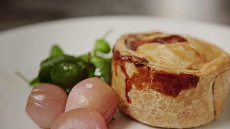A-Pork-pie-is-served-on-a-plate-with-two-picked-onions