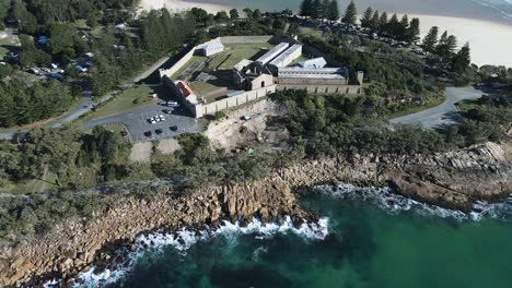 Aerial-view-over-water-of-the-heritage-listed-former-public-works-prison-built-on-a-coastal-headland