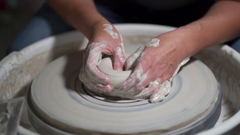 Person-is-doing-pottery-class,-forming-the-shape-of-it-while-it-spins-very-fast