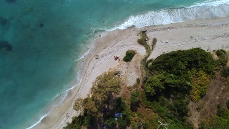 Drone-shot-of-an-Albanian-beach---drone-is-descending-in-birds-eye-view,-approaching-a-parasol