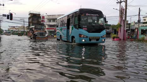 Public-and-private-vehicle-driving-on-flood-highway,-after-tropical-storm-in-Dagupan-City,-Philippines