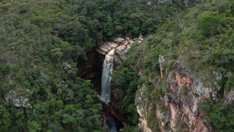 Aerial-drone-descending-shot-of-the-incredible-Mosquito-Falls-surrounded-by-tropical-jungle-and-cliffs-in-the-Chapada-Diamantina-National-Park-in-Northeastern-Brazil-on-a-warm-sunny-summer-day