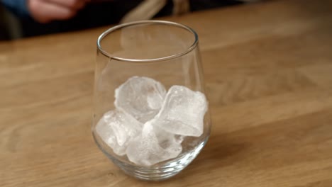 Ice-cubes-fall-into-glass-as-bartender-makes-a-drink
