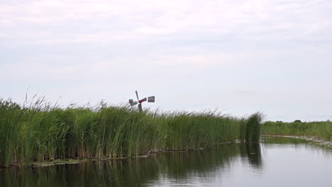 POV-Einer-Ruhigen-Bootsfahrt-Durch-Schilf-Mit-Einer-Windmühle-Im-Hintergrund,-Niederlande