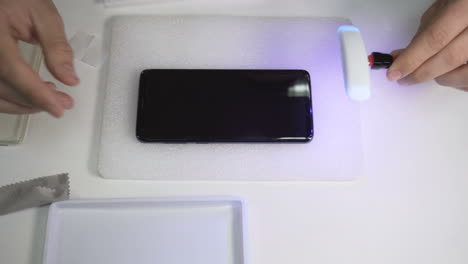 Mann-Nutzt-UV-Taschenlampe,-Um-Den-Bildschirm-Eines-Smartphones-Zu-Schützen