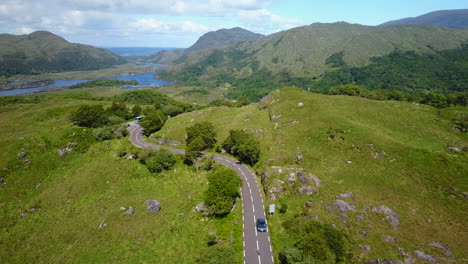 Rising-aerial-video-of-tourists-driving-along-winding-roads-on-rugged-scenery-with-lakes-and-mountains-in-background,location-Killarney-National-Park