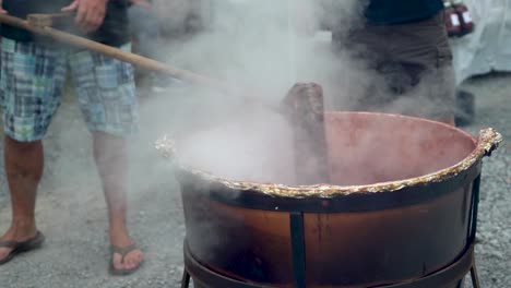 Very-tight-shot-of-stirring-steaming-apple-butter-in-a-large-black-cauldron-outside