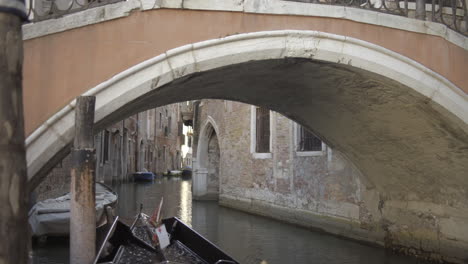 Empty-gondola-parked-under-small-bridge,-Venice-Italy