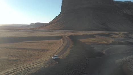 Aerial-Orbit-Shot-of-a-Tourist-Getting-Out-of-a-Parked-Car-in-a-Vast-Landscape