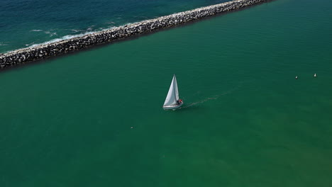 Drone-footage-of-a-sailboat-heading-out-to-sea