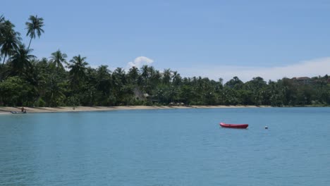 Kayak-Rojo-Vacío-Flotando-Cerca-De-La-Orilla-Del-Océano-De-Una-Playa-Remota-En-Tailandia