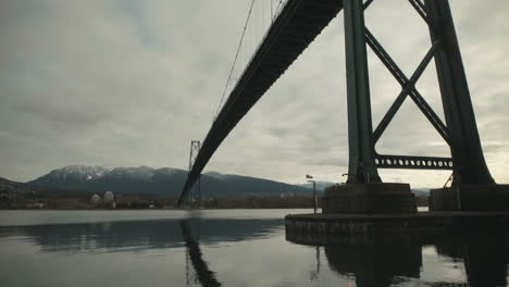 Wide-shot-Under-Lions-Gate-suspension-Bridge-in-Stanley-Park,-Vancouver,-Cloudy,-Slowmotion