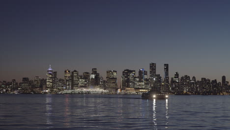 Sea-bus-approaching-Lonsdale-Quay,-Vancouver-skyline-at-dusk-in-background