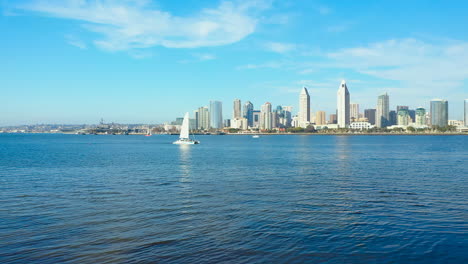 Luftaufnahme-Eines-Segelboots-In-Der-Bucht-Von-San-Diego-Mit-Der-Skyline-Der-Stadt-Im-Hintergrund