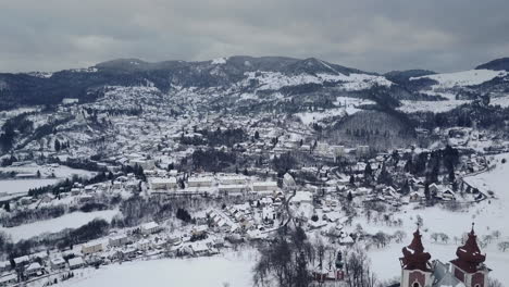 Flying-towards-old-mining-town-Banska-Stiavnica-above-Calvary-Church,-Winter