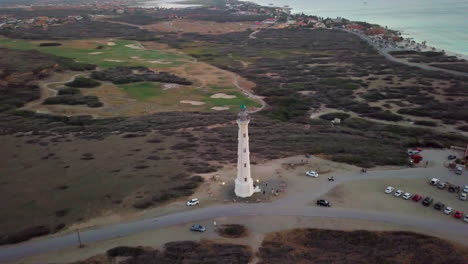 Aerial-sweeping-shot-of-the-golf-course-and-a-radio-tower-behind-the-California-Lighthouse-in-Noord,-Aruba