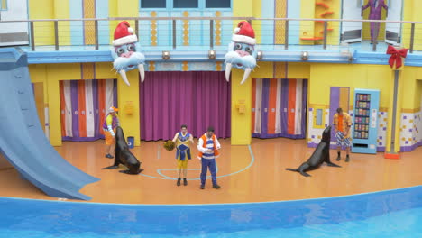 A-Kids-Show-with-Grey-Seals-Performing-on-Stage-with-Trainers-at-SeaWorld,-Slow-Motion-Static-Shot