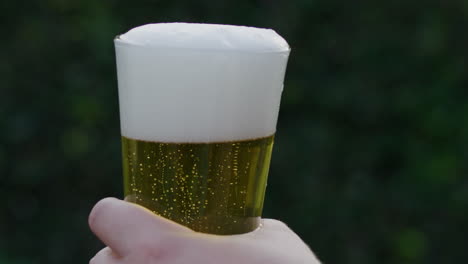 SLOW-MOTION-video-raising-a-filled-glass-of-beer-with-blurred-background