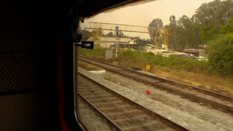 Steady-side-point-of-view-shot-of-an-Indian-train-compartment-window,-while-the-train-is-moving-and-arriving-at-the-station