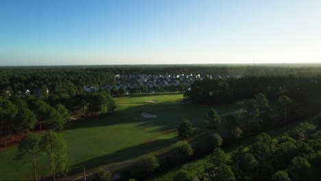 Drone-flying-away-from-houses-located-on-golf-course-in-early-morning