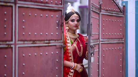 Eine-Lächelnde-Indische-Bengalische-Braut-Kommt-Von-Außerhalb-Eines-Großen-Tors-Herein
