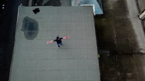 Direct-Overhead-Aerial-Drone-Shot-of-Young-Adult-Male-Parkour-Free-Runner-Doing-Spins-on-an-Abandoned-Roof-Top