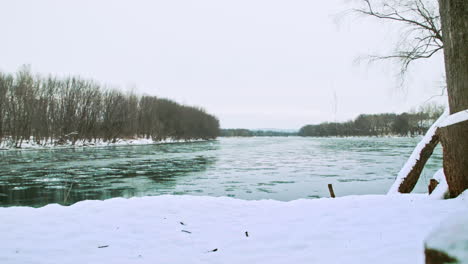 Eis-Schwimmt-Flussabwärts-Mit-Schneebedecktem-Ufer-Im-Vordergrund