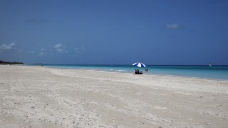 Awesome-beach-of-Varadero-during-a-sunny-day,-fine-white-sand-and-turquoise-and-green-Caribbean-sea,on-the-right-one-blue-parasol,Cuba