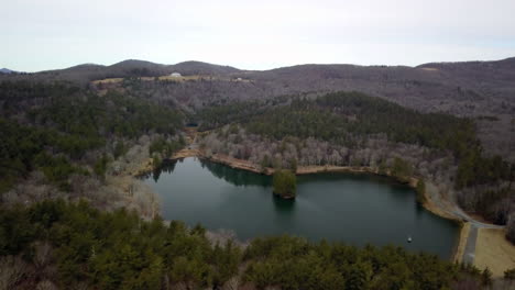 Aerial-of-Bass-Lake-near-Blowing-Rock-North-Carolina-with-Moses-Cone-Estate-atop-the-hilltop-in-the-background