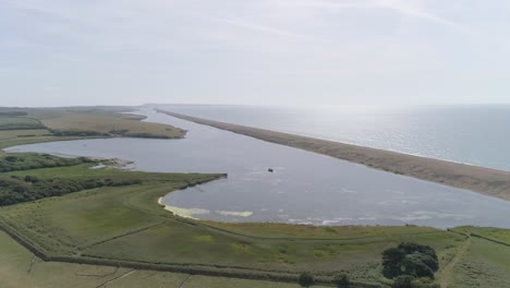 Aerial-tracking-from-right-to-left-along-Chesil-Beach-and-the-fleet-lagoon-rotating-the-shot-out-to-sea-and-the-oncoming-sunshine