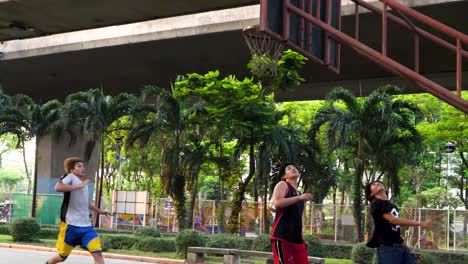 Kinder-Spielen-Basketball-Unter-Der-Autobahn-Im-Bezirk-Saphan-Taksin-In-Bangkok,-Thailand,-In-Zeitlupe