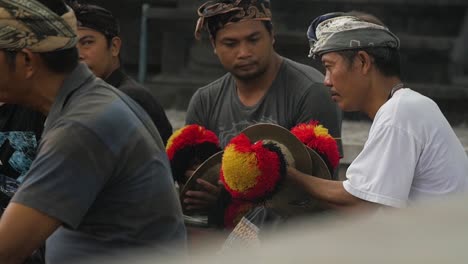 Slow-motion-of-Balinese-musicians-with-decorative-coloured-pom-pom's-on-cymbals-playing-outdoors-in-ceremonial-event