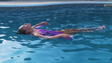 Young-girl-relaxing-in-a-swimming-pool-on-a-noodle