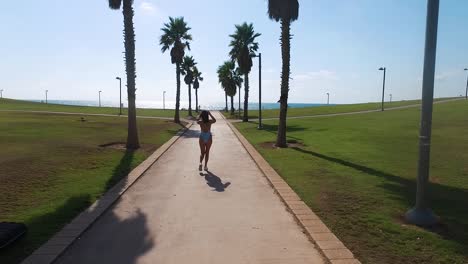 Girl-walking-through-the-palm-trees.-Drone-slow-motion