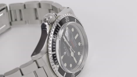 footage-of-an-original-Rolex-Submariner-watch,-rotating-on-a-white-turntable-display