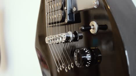 Black-electric-guitar-body-hanging-on-a-wall,-CLOSE-UP
