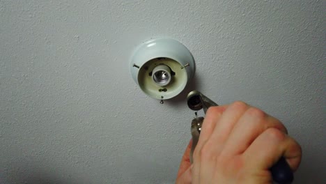 Removing-the-broken-part-of-a-light-bulb-with-a-pair-of-pliers-and-looking-at-the-broken-bulb