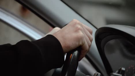 Man-putting-his-hands-on-a-black-leather-steering-wheel-and-holding-it-tight