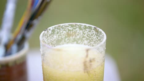 Dipping-and-Tapping-Paint-Brush-in-Water-Glass-Close-Up