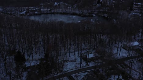 Drone-flyover-mountain-homes-in-forest-with-frozen-pond