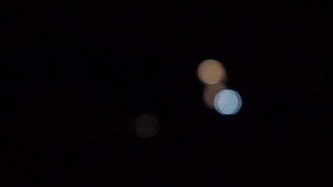 Car-headlights-out-of-focus,-bokeh-balls-moving,-night-time