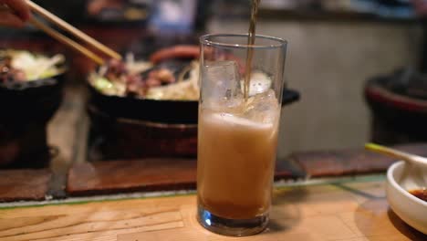 pouring-ginger-beer-into-a-glass-full-of-ice-at-a-Japanese-Jingisukan-restaurant