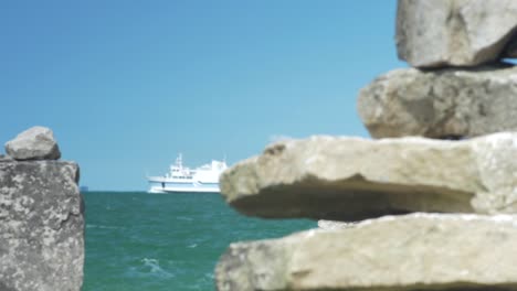 Rack-focusing-shot-from-an-Inuksuk-to-a-white-ferry-cruising-in-the-sea-behind